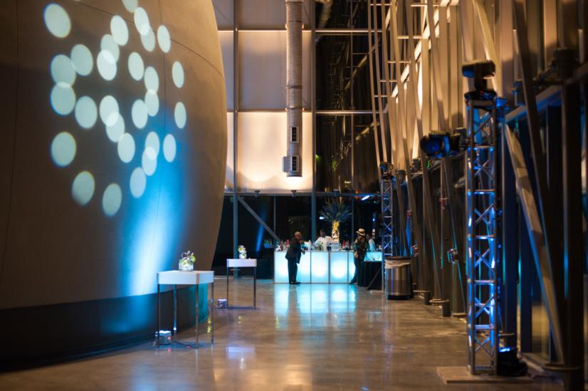 Planetarium lobby during evening reception shows the side of the large dome exterior on the left with circular lights projected on it