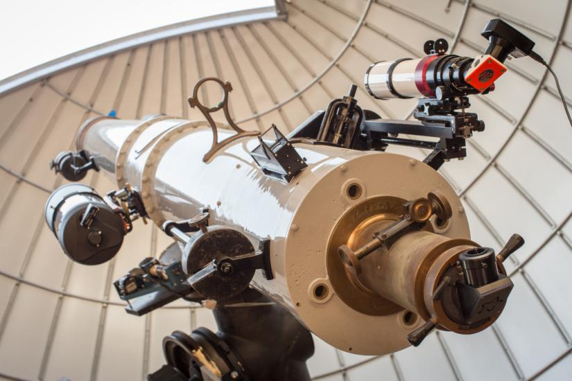 Large white telescope points towards the afternoon sky through an open observatory dome