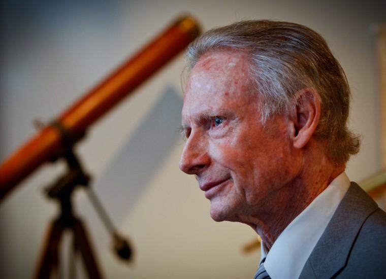 Older man in profile with wooden telescope in the background