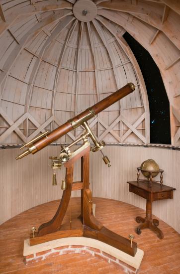 Brass and wood telescope stands on base under a fake observatory dome