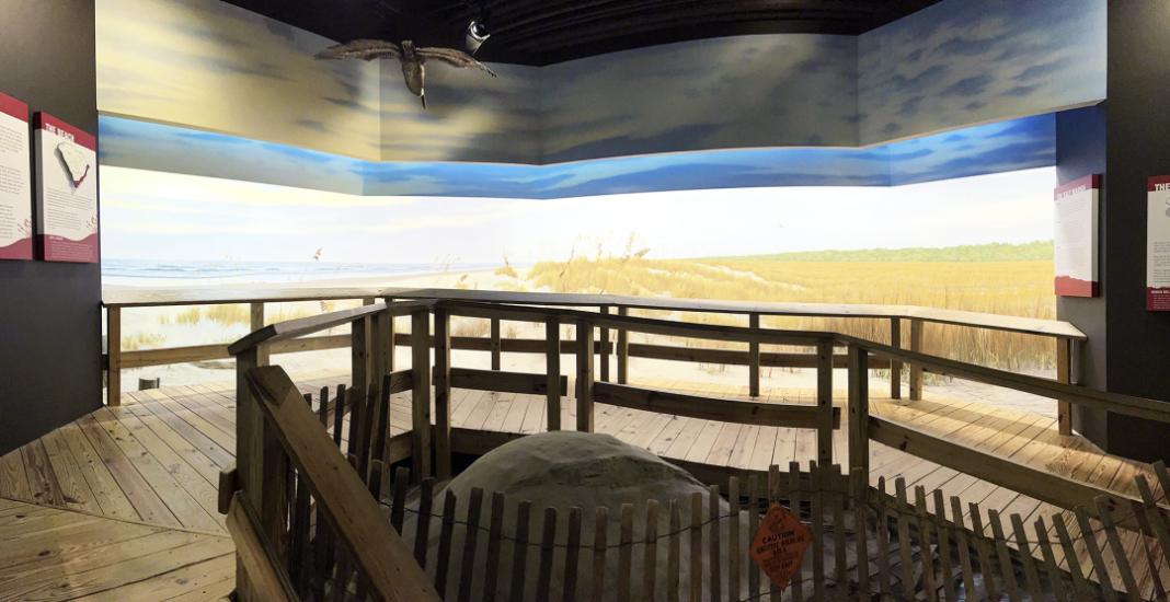 Wooden walkway in foreground with area behind it painted to appear like a lowcountry South Carolina beach