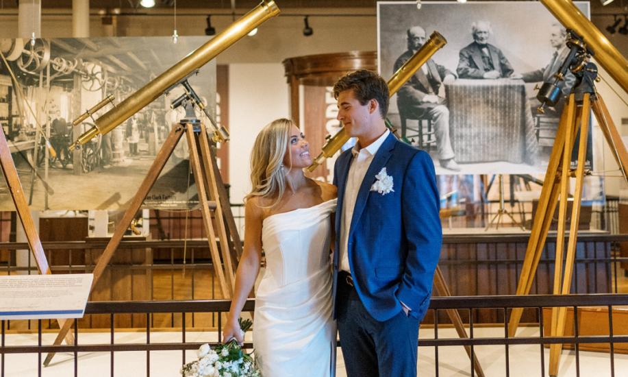 Bride and groom pose in front of telescopes on display at the South Carolina State Museum
