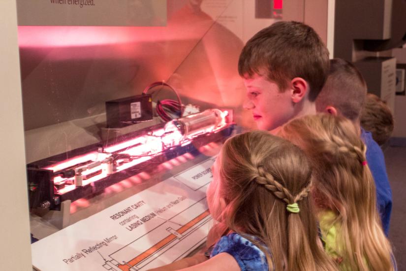 Two boys and two girls observing a maser and laser demonstration display