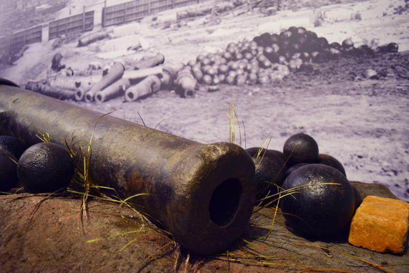 Large antique cannon on exhibition with photo backdrop of a destroyed Main St. in Columbia, SC c. 1865