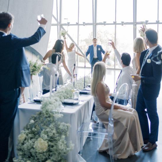 Wedding Party Welcomes Bride and Groom as they enter reception in the planetarium lobby