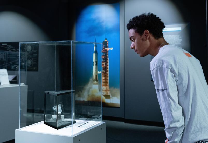 Individual looking at some moon rock inside of a glass case
