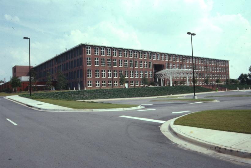 Large, four story brick building with large windows from end to end on each floor.