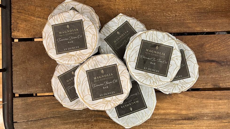 Multiple Round Bars of Soaps Wrapped in White Paper With a Brown Label Reading Magnolia Soaps