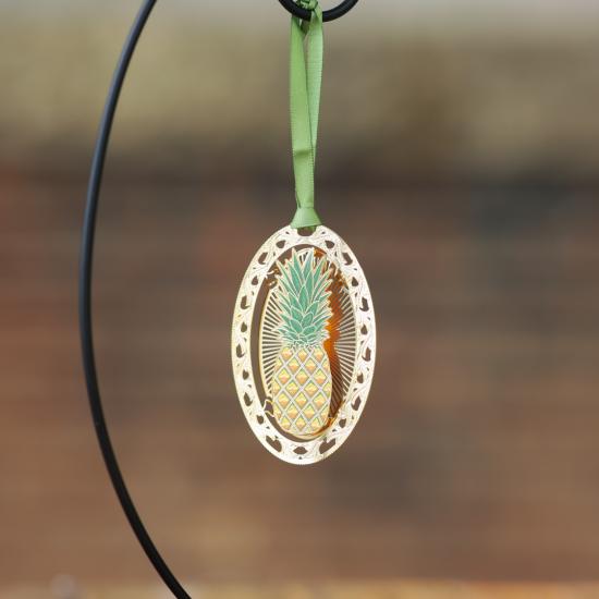 Oval Shaped Metal Ornament With Pineapple in the Center of the Oval