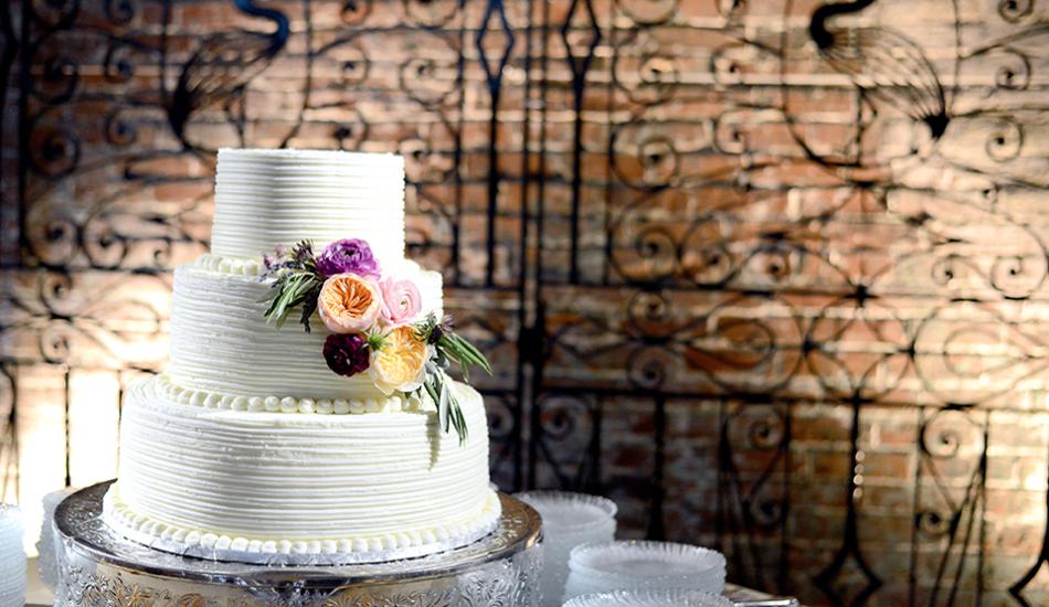 3 Tiered white wedding cake sits in front of the Philip Simmons wrought iron gate at the State Museum.