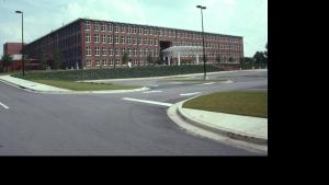 Large, four story brick building with large windows from end to end on each floor.